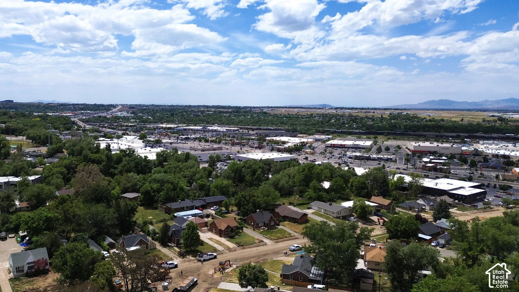 Aerial perspective featuring mature trees, residential infrastructure, and mountain topography in the distance