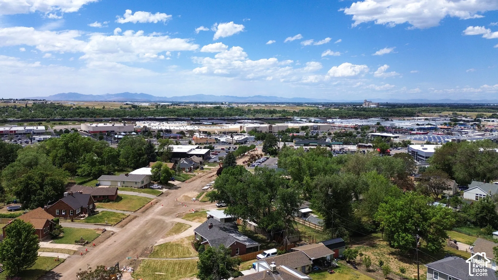 Aerial perspective featuring mature tree canopies, residential streets, and mountain range backdrop