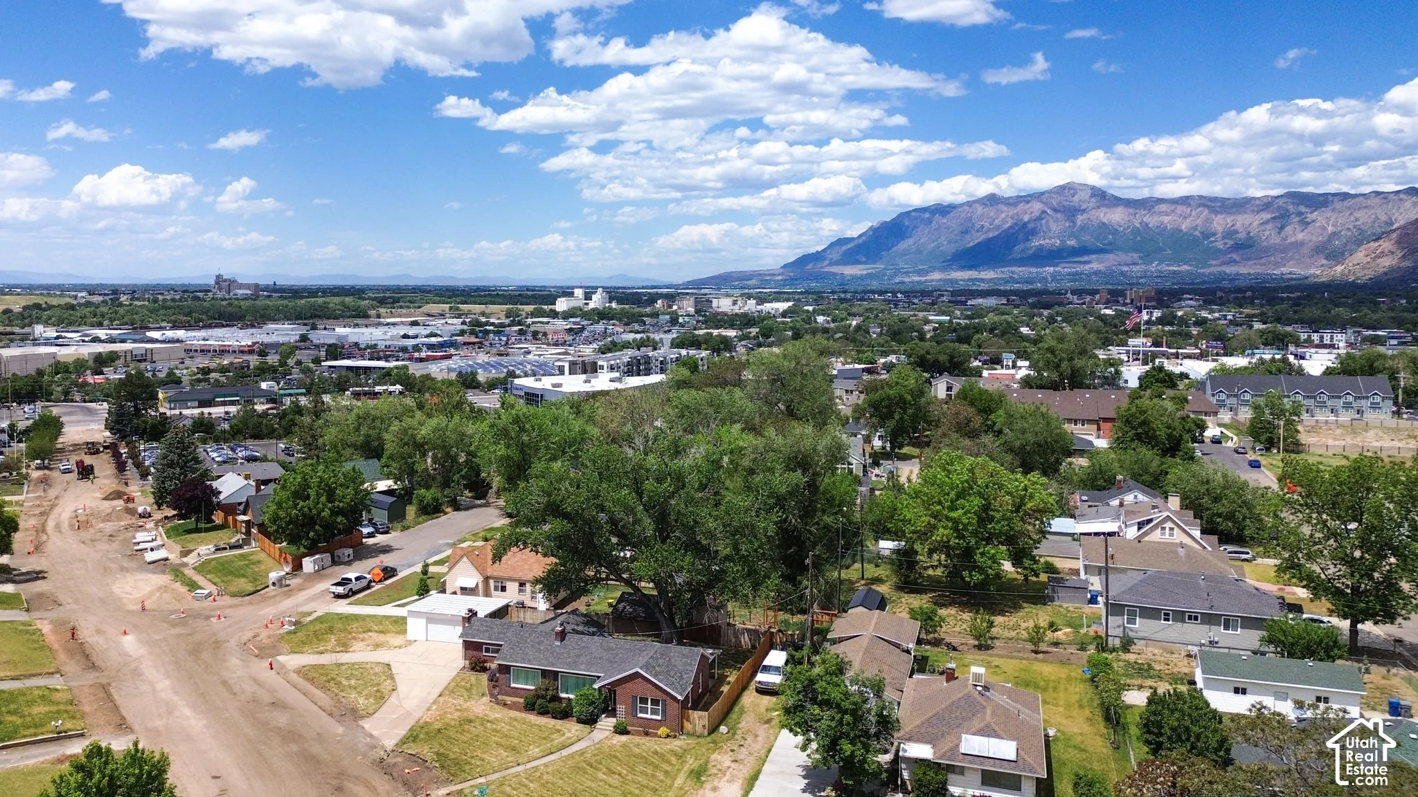 Aerial perspective showcasing brick exterior construction, asphalt shingle roofing, and established mature tree canopy, set against a prominent mountain backdrop