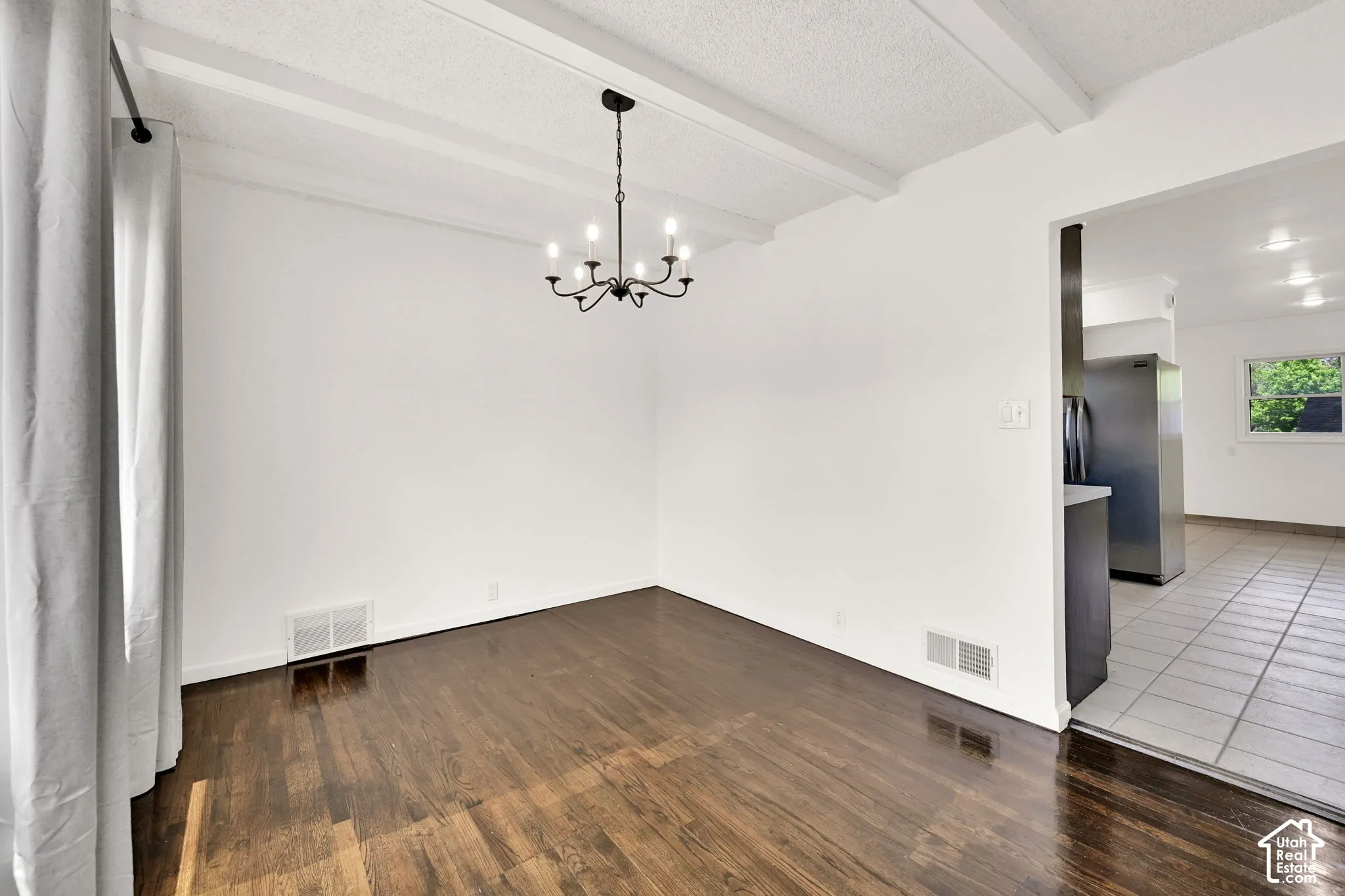 Wood-finish flooring, exposed ceiling beams, and a multi-arm chandelier fixture