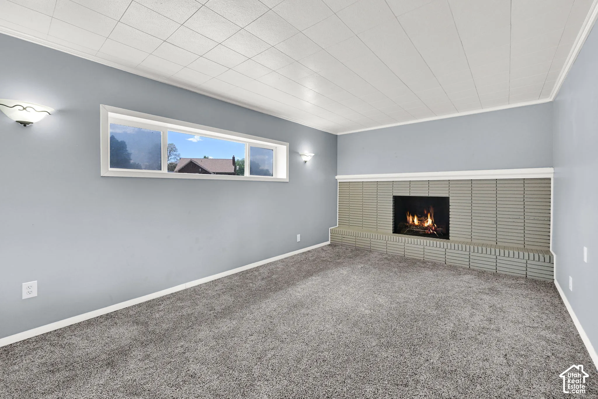Room featuring a floor-to-ceiling textured tile fireplace surround, horizontal picture window, recessed ceiling paneling, and wall-mounted light fixtures