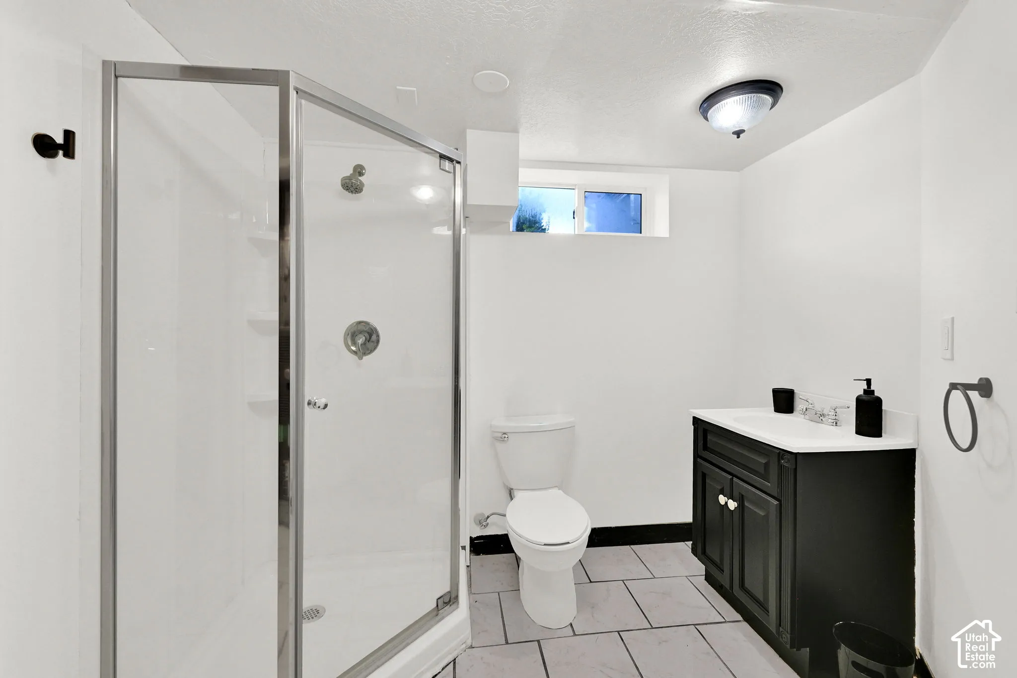 Bathroom featuring a corner shower enclosure, vanity with a white countertop, ceramic tile flooring, and a flush-mount ceiling light fixture