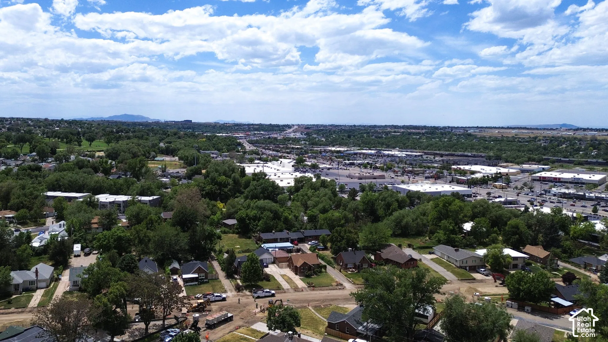 Aerial perspective featuring an established suburban landscape with mature trees, street grids, and a mountainous backdrop