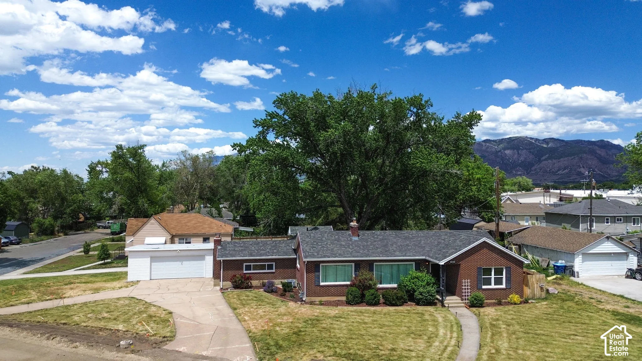Single-story brick residence featuring an attached two-car garage, concrete driveway, and mountain backdrop