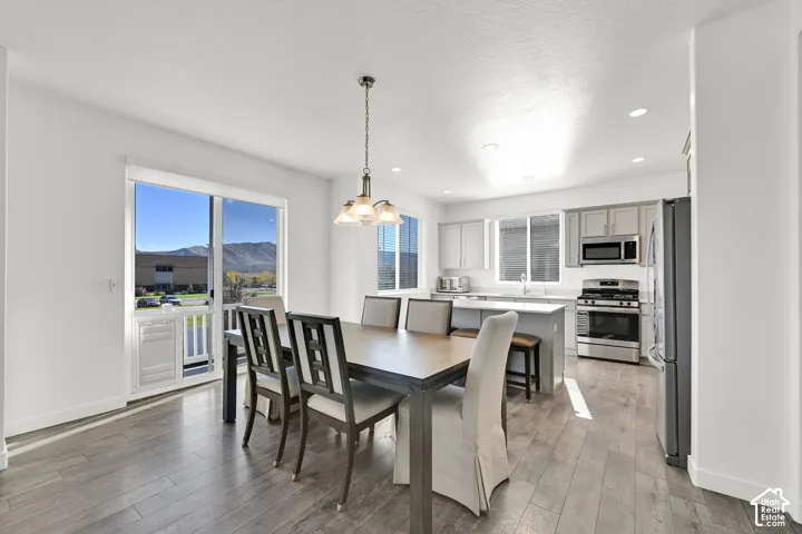 Open-concept interior featuring wood-finish flooring, grey cabinetry, stainless steel appliances, recessed lighting, and a sliding glass door with mountain scenery