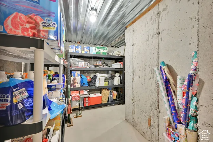 Storage area featuring concrete walls, a corrugated metal ceiling, and a concrete floor