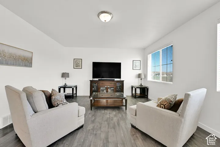 Living area featuring wood-finish flooring, neutral walls, flush-mount lighting, and large windows with horizontal blinds