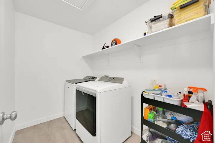 Laundry area featuring neutral-toned flooring, white walls, and an overhead built-in storage shelf