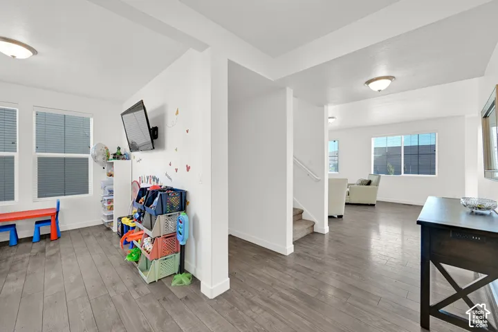Open-concept interior featuring wood-finish flooring, dual-pane windows, recessed lighting, and a staircase with a white handrail