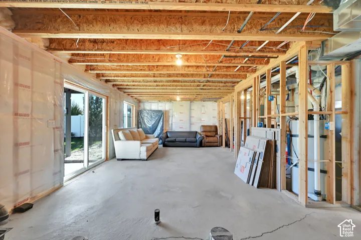 Unfinished lower level featuring exposed wood joist ceilings, concrete flooring, sliding glass door, and insulation-wrapped walls