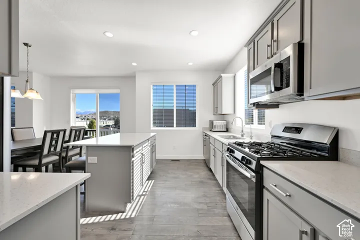 Kitchen featuring light-gray cabinetry, solid surface countertops, a central island, recessed lighting, and wood-finish flooring