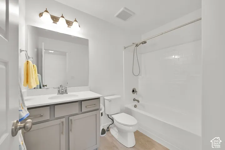 Bathroom featuring a vanity with shaker-style cabinetry and a light-toned countertop, an integrated sink, a full-width mirror, and a tub-shower combination with subway-tile style surround