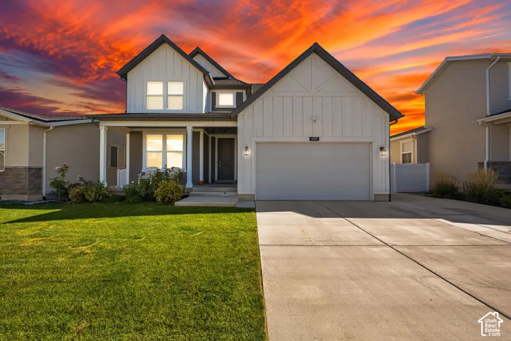 Two-story exterior featuring white vertical siding, a covered front porch, an attached garage, and a concrete driveway