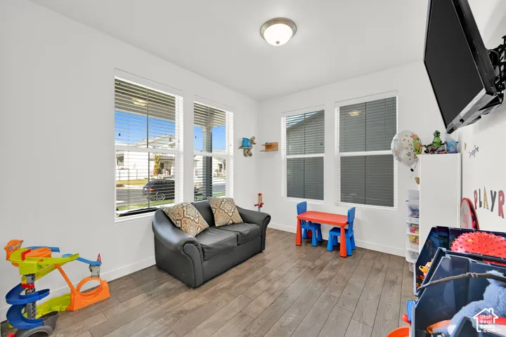 Room featuring wood-finish flooring, four windows with installed blinds, and a flush-mount ceiling light fixture
