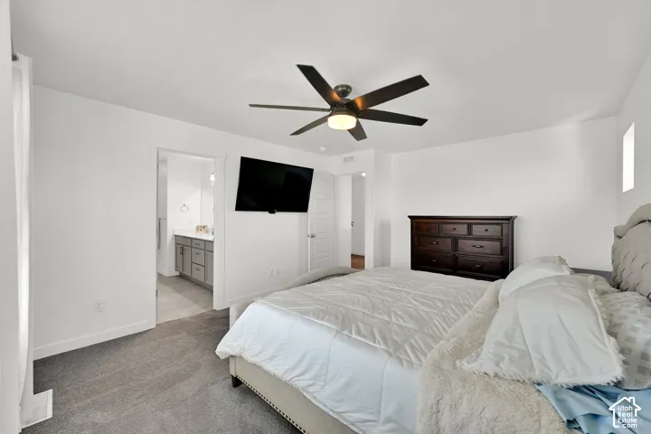 Bedroom featuring neutral-toned carpeting, a multi-blade ceiling fan with integrated lighting, and a solid-core panel door