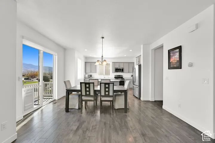 Kitchen and dining area featuring wood-finish flooring, gray shaker-style cabinetry, stainless steel appliances, a kitchen island, and sliding glass doors to a balcony