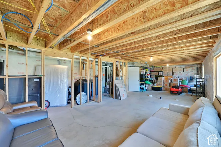 Unfinished basement featuring exposed wood joists, concrete flooring, and wooden wall framing
