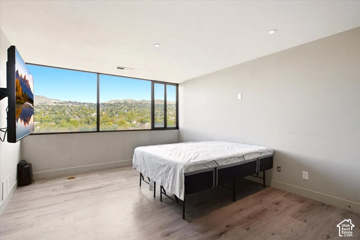 Expansive floor-to-ceiling windows, wood-finish flooring, and recessed ceiling lighting