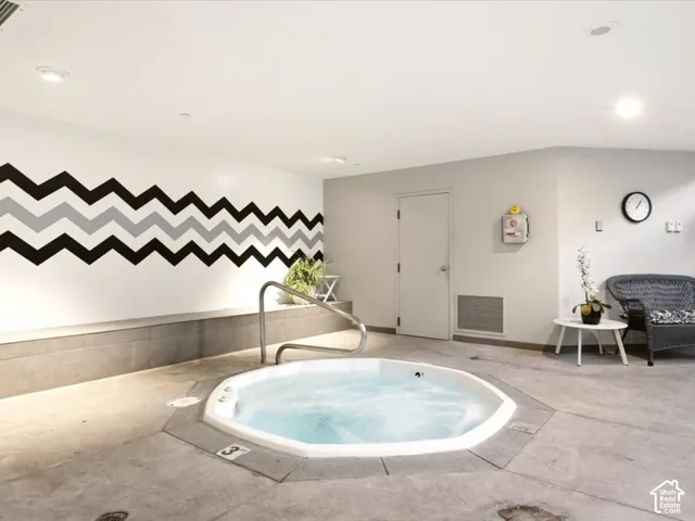 Indoor spa featuring an octagonal jetted tub, stainless steel grab bar, concrete-finish flooring, and recessed ceiling lighting