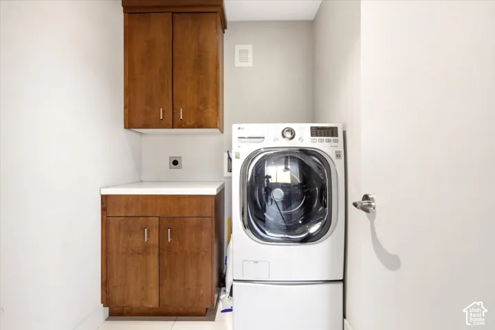 Laundry area featuring wood-finish cabinetry, solid-surface countertop, and integrated storage