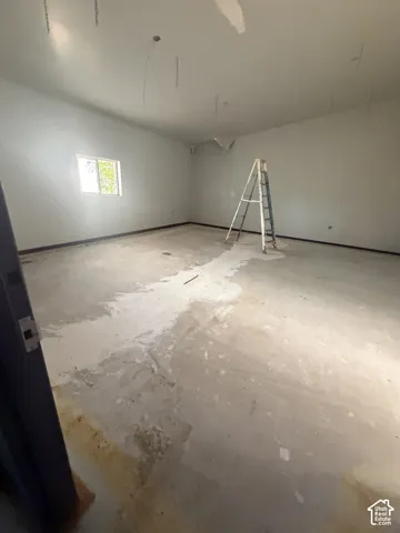 Open-concept interior featuring smooth-finish walls, concrete flooring, and a single-pane window
