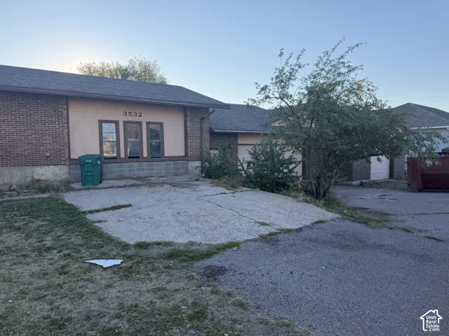 Exterior featuring a brick and stucco facade, multi-gabled roofline, concrete driveway, and attached garage