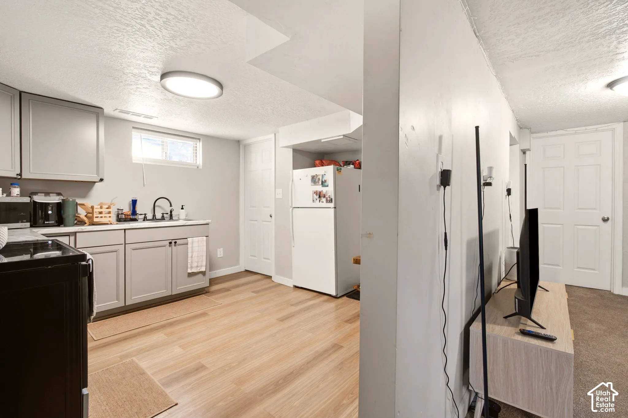 Kitchen featuring gray shaker-style cabinetry, wood-finish flooring, a matte black kitchen faucet, and a flush-mount overhead light fixture