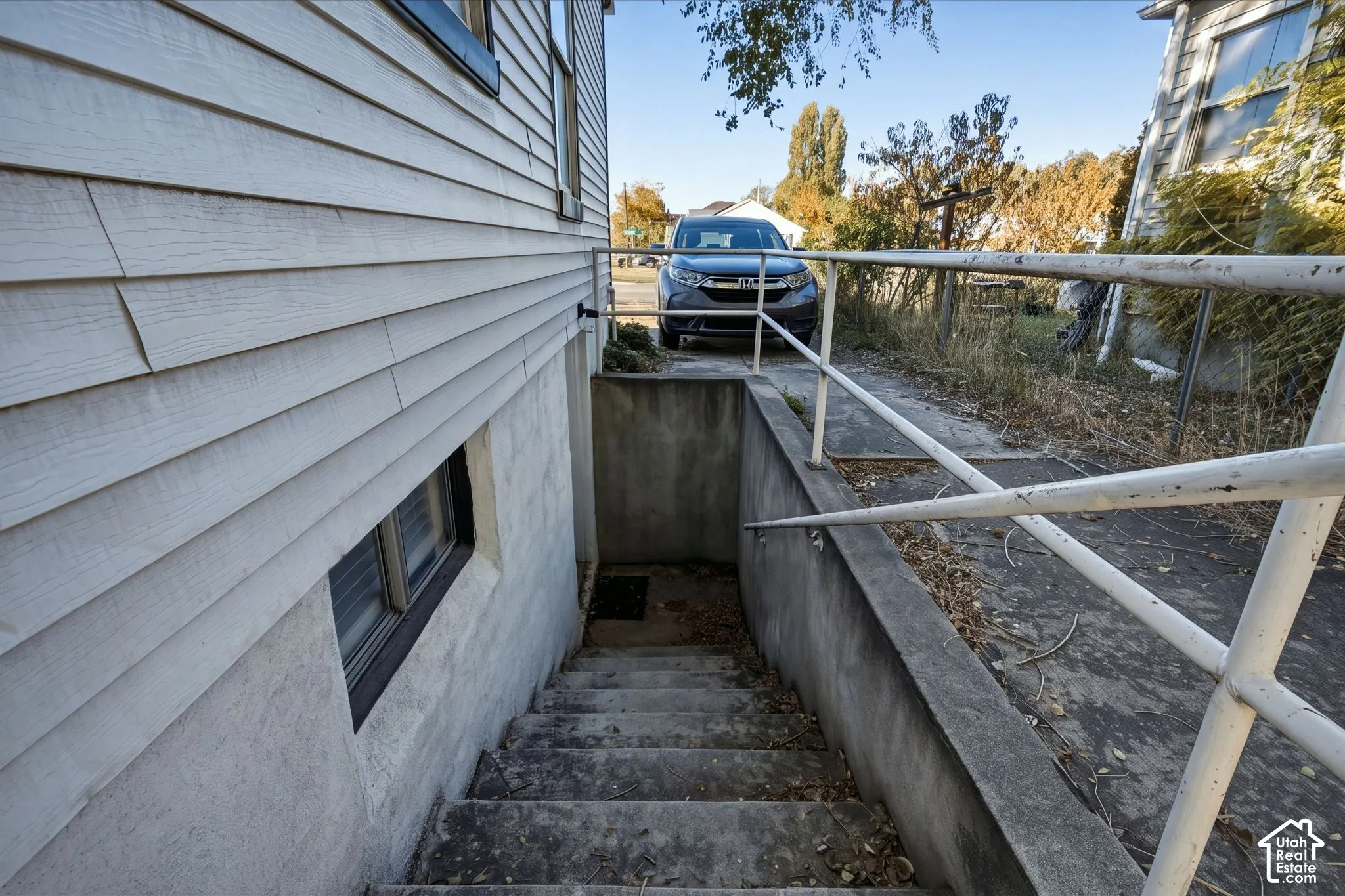 Exterior concrete stairwell with metal handrails, horizontal lap siding, and concrete retaining wall