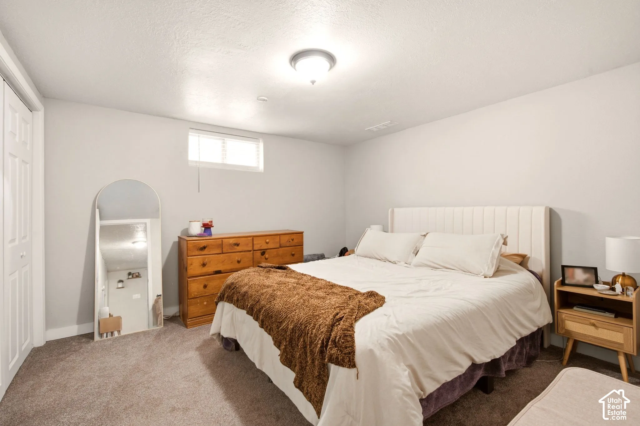 Neutral-toned interior space featuring carpeting, ceiling-mounted lighting, and a horizontal sliding window