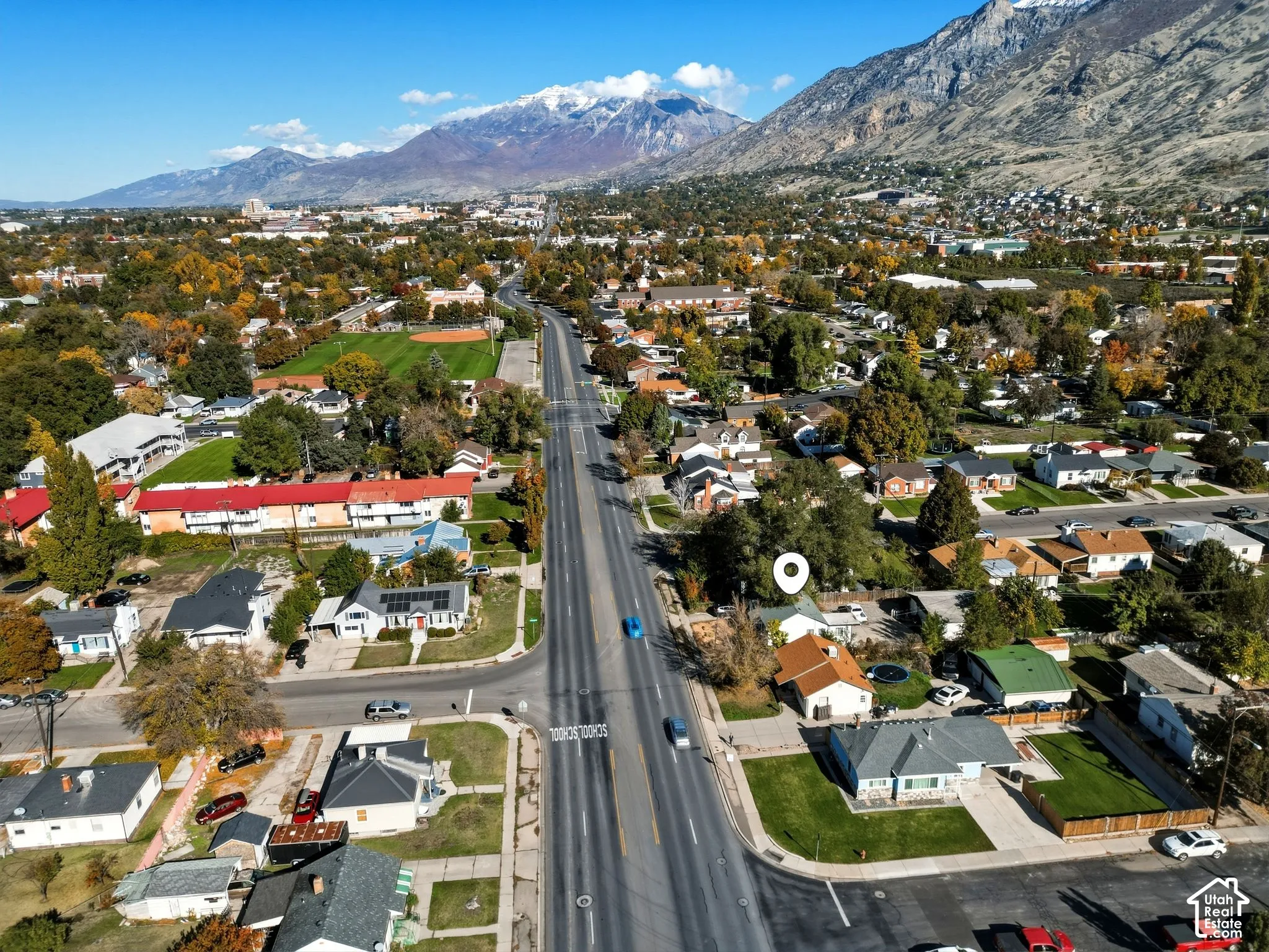 Aerial perspective featuring a single-family home with a detached garage, corner lot positioning, and a prominent mountain range backdrop