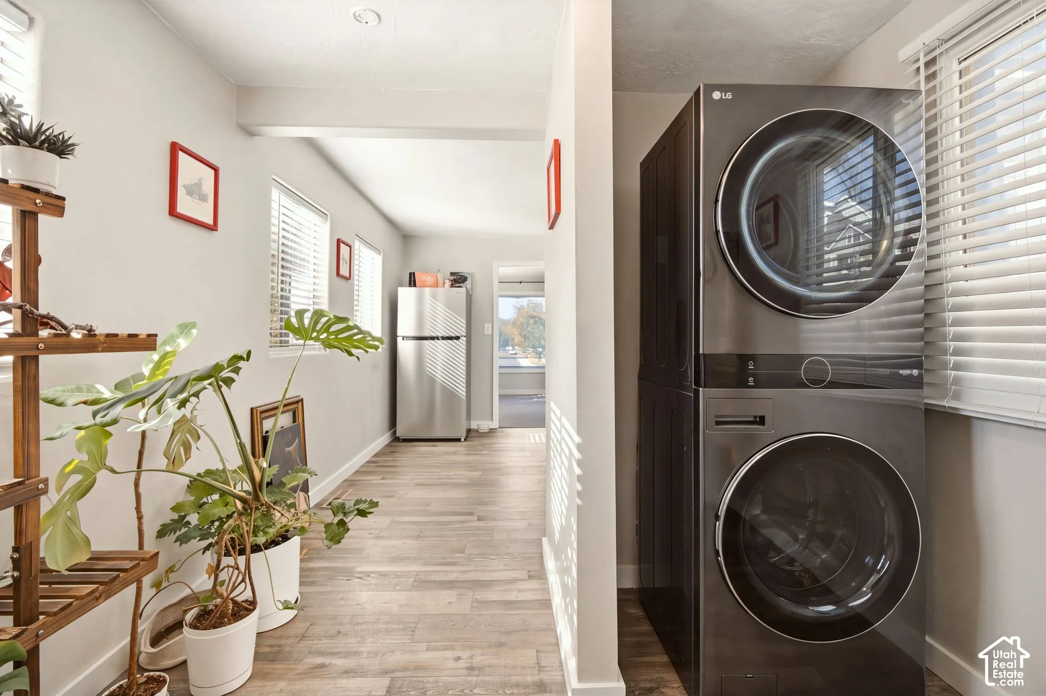 Stacked dark-finish washer and dryer unit, wood-finish flooring, and recessed ceiling lighting