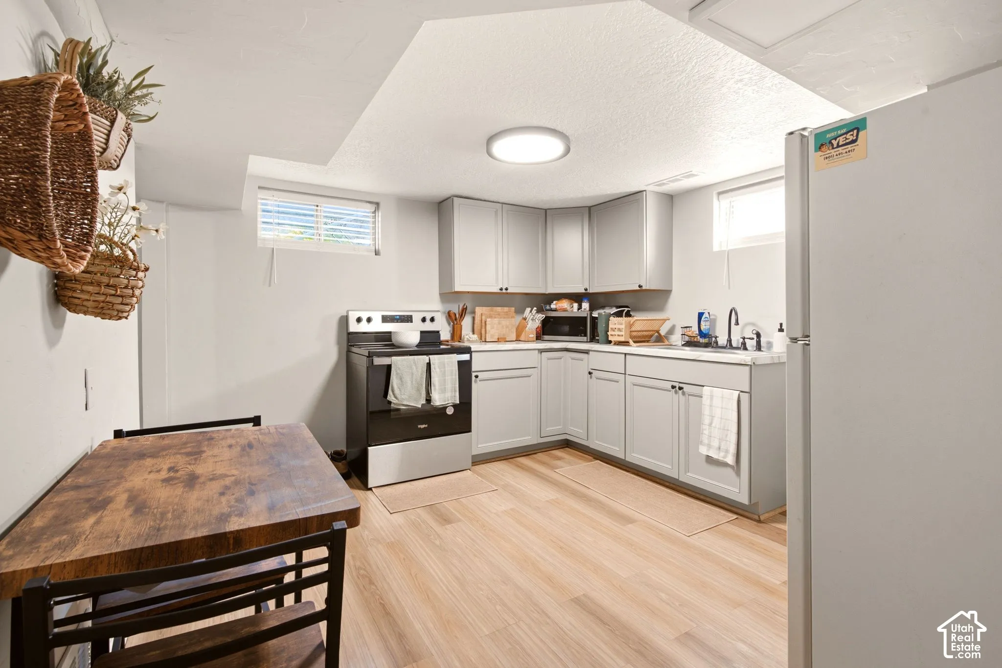 Kitchen featuring light grey cabinetry, wood-finish flooring, a stainless steel electric range, and solid-surface countertops
