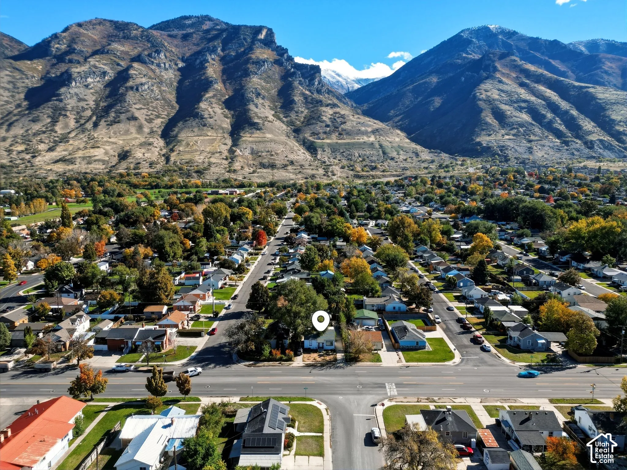 Aerial perspective showcasing a residential property set against a prominent mountain backdrop with mature trees