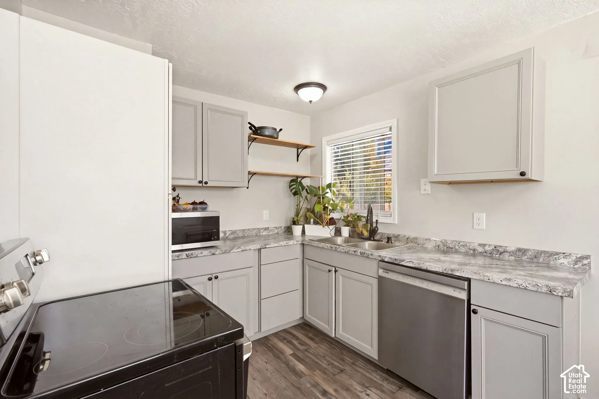 Kitchen featuring shaker-style grey cabinetry, stone-patterned laminate countertops, stainless steel dishwasher, wood-finish flooring, and floating open shelving