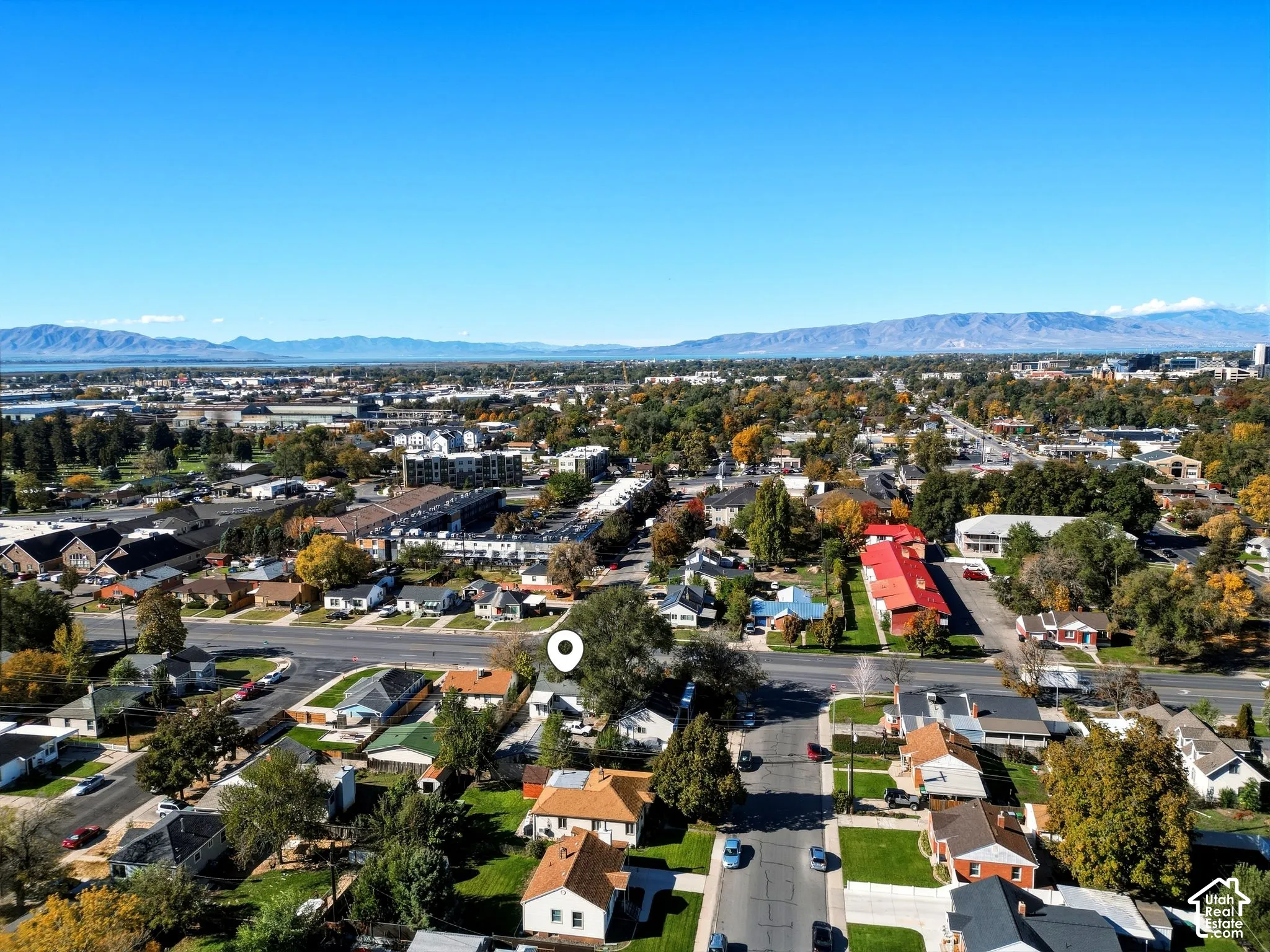 Aerial perspective featuring a residential lot with mature trees and a mountain range backdrop