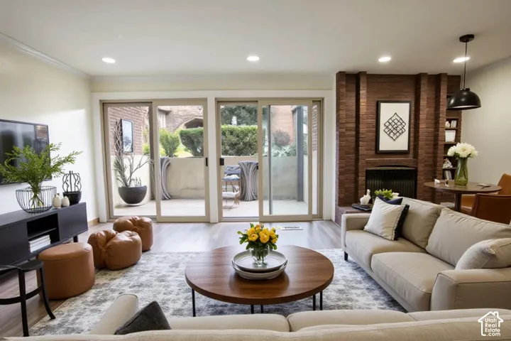 Floor-to-ceiling brick fireplace, wood-finish flooring, recessed lighting, and dual sliding glass doors providing access to the exterior patio
