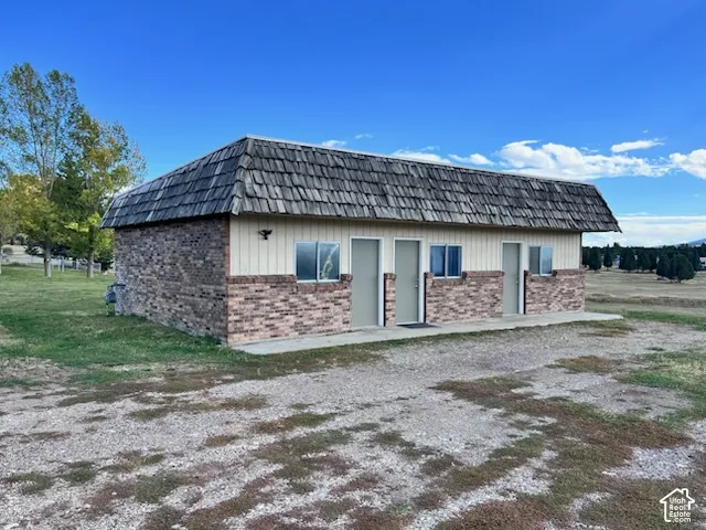 Detached structure featuring a multi-tonal brick and vertical siding exterior, wood shake roofing, and multiple entry points