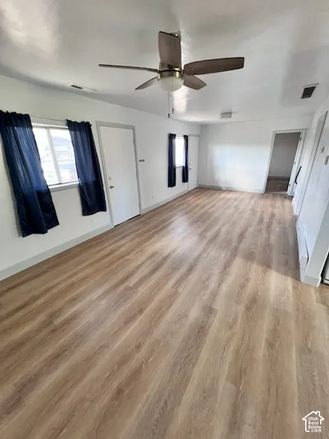 Wood-finish flooring, neutral walls, and a ceiling-mounted fan with integrated lighting