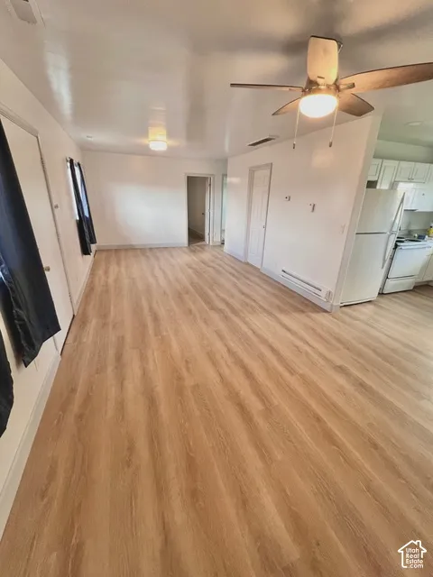 Interior space featuring wood-finish flooring, white cabinetry, ceiling fan with integrated lighting, and flush-mount lighting