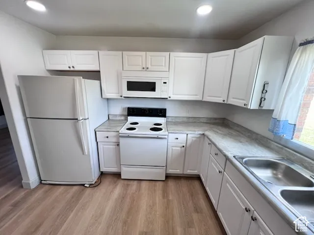 Kitchen featuring white cabinetry, stone-finish countertops, wood-finish flooring, dual-basin stainless steel sink, and white appliances