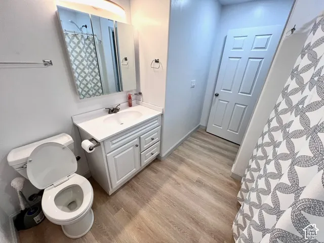 Bathroom featuring wood-finish flooring, white cabinetry with an integrated countertop sink, wall-mounted medicine cabinet, and a six-panel door