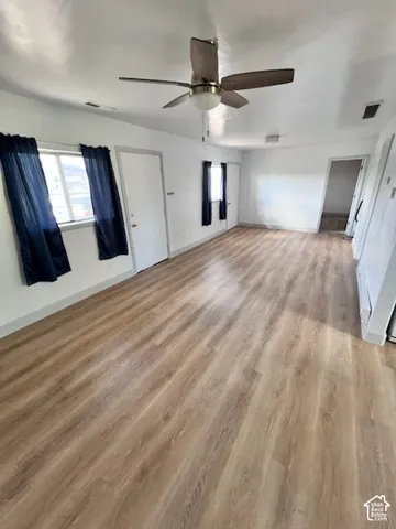 Wood-finish flooring, neutral walls, and a ceiling-mounted fan with integrated lighting