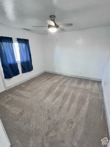 Neutral-toned carpeting, white walls, and a brushed metal ceiling fan with integrated light fixture