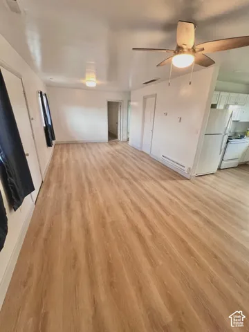 Interior space featuring wood-finish flooring, white cabinetry, ceiling fan with integrated lighting, and flush-mount lighting