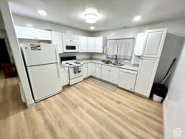 Kitchen featuring white shaker-style cabinetry, wood-finish flooring, recessed lighting, stone-patterned countertops, and a dual-basin stainless steel sink