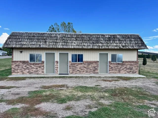 Single-story structure featuring a wood shake roof, vertical siding, brick masonry exterior, and a concrete apron