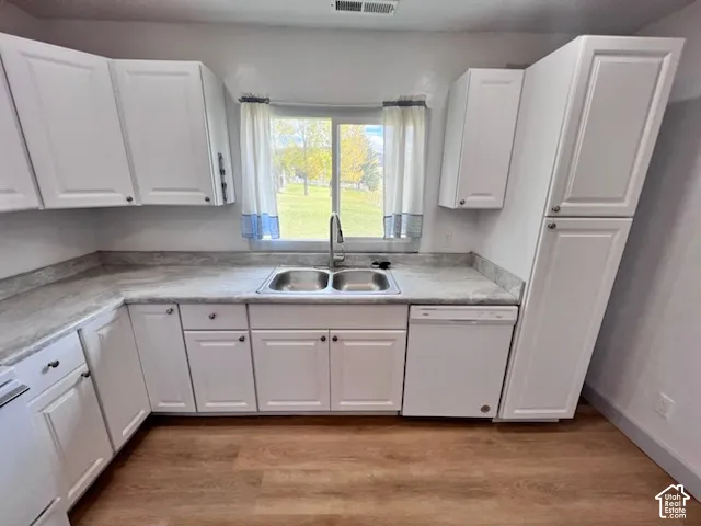 Kitchen featuring white cabinetry, stone-finish countertops, stainless steel dual-basin sink with pull-down faucet, built-in dishwasher, and wood-finish flooring