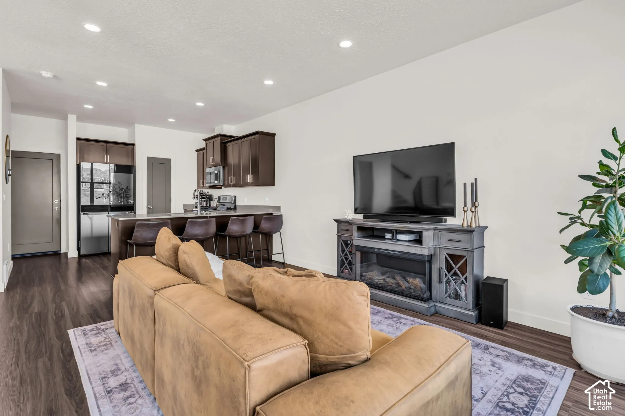 Open-concept living space featuring wood-finish flooring, recessed lighting, and cabinetry with an integrated breakfast bar