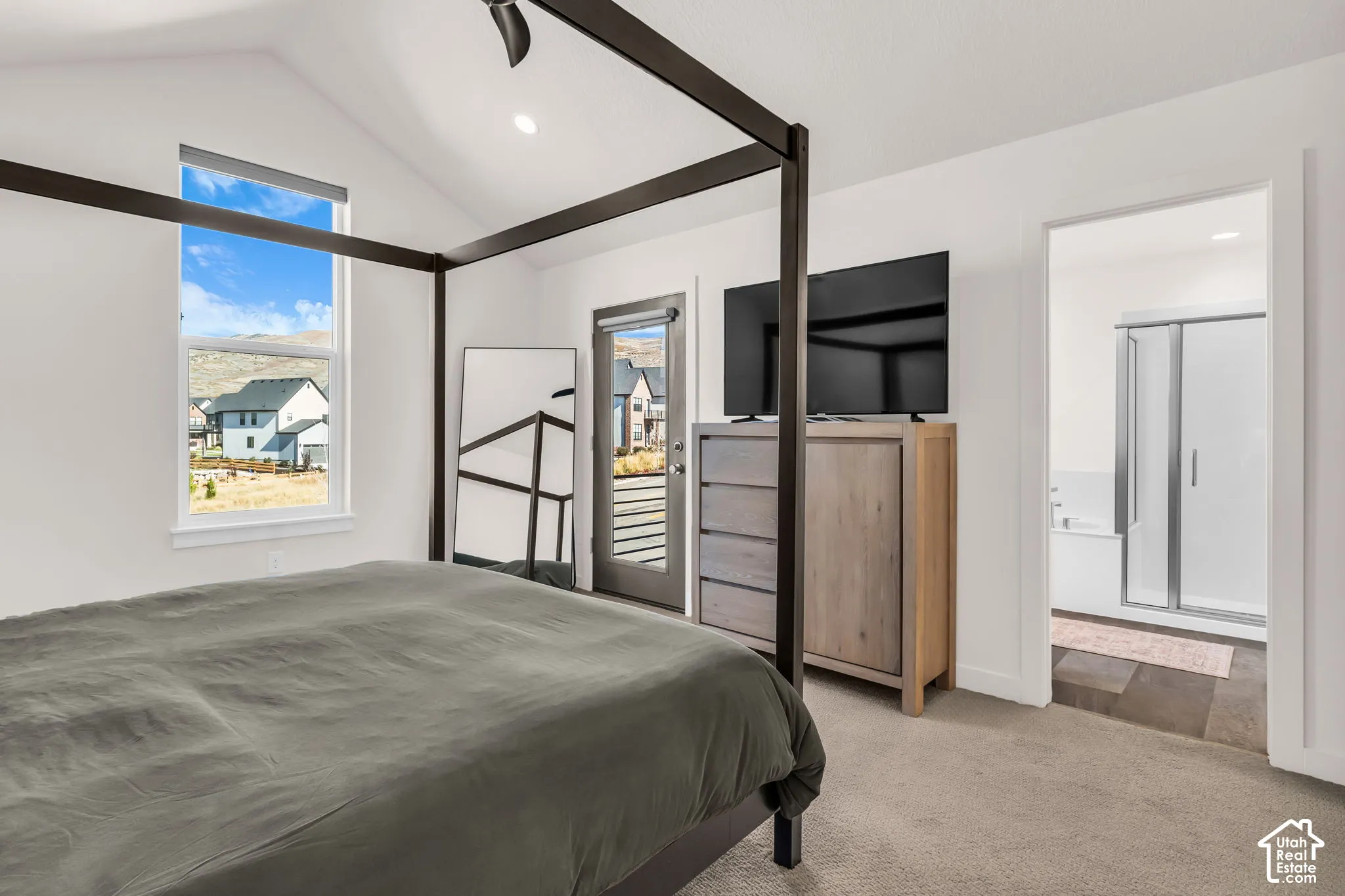 Vaulted ceilings, neutral carpeting, recessed lighting, and a private exterior door
