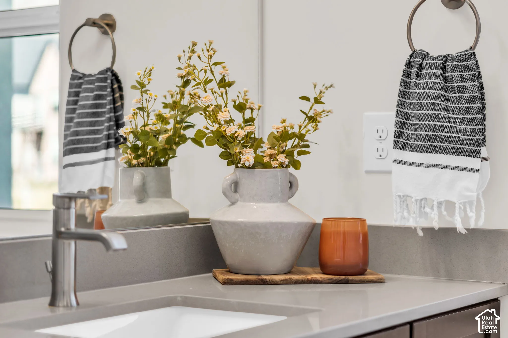 Quartz countertop featuring an integrated rectangular undermount sink, brushed nickel single-handle faucet, large-scale wall-mounted mirror, and matching metallic ring towel holders